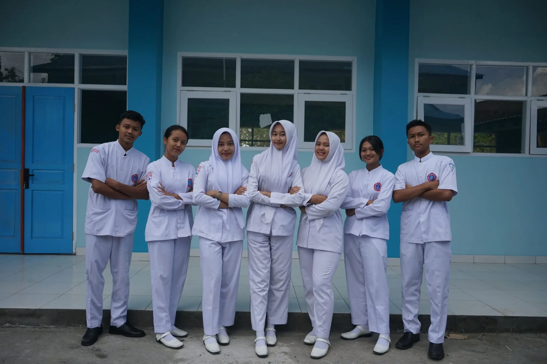 Siswa-siswi berseragam praktik putih berfoto bersama di depan gedung sekolah